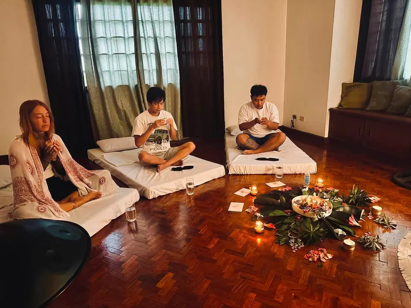 Guests resting on mattresses by candlelight during a deep journey