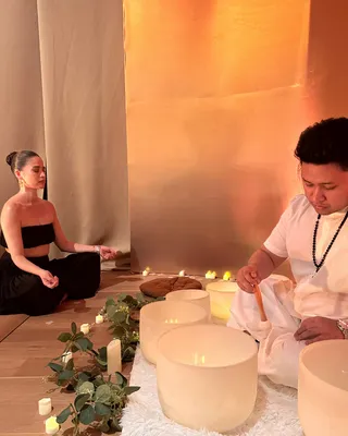 Anne Curtis seated in meditation during a candlelit Tallaro sound bowl session