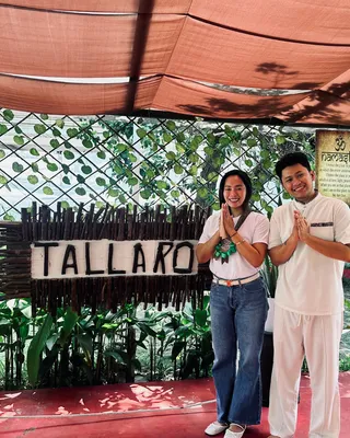Dr. Femilyn S. Domingo greeting a Tallaro facilitator beside the Tallaro sign in the garden