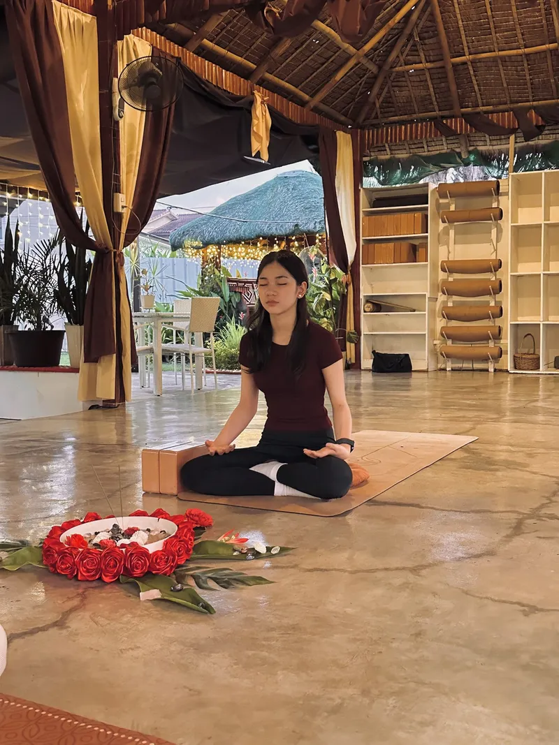 A teen meditating cross-legged on the pavilion floor